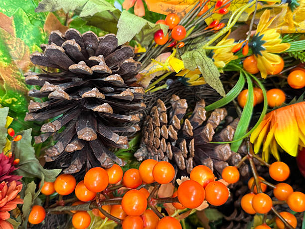 istock Full frame image of autumn decoration display wreath, green eucalyptus and artificial foliage, autumnal coloured maple leaves, dried pinecones, fake berries, yellow and orange flowers, autumnal background wallpaper, focus on foreground 2227644083
