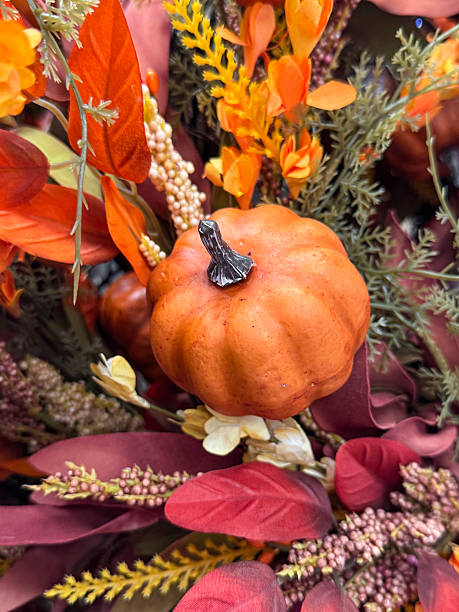istock Full frame image of autumn decoration display wreath, artificial foliage, autumnal coloured leaves, plastic orange pumpkin, fake berries, autumnal background wallpaper, focus on foreground 2227644149