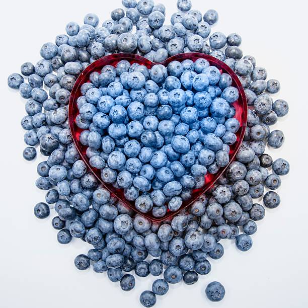 Blueberries in heart shaped bowl on white background