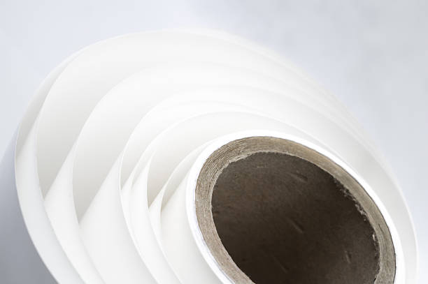 White polygraph paper on a cardboard core. A bundle of leftover paper in a printing house. Material for the printing industry. Selective focus.