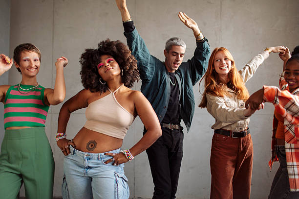 A diverse group of Gen Z individuals, including men and women, posing and dancing joyfully in casual attire inside a minimalist photography studio, emphasizing energy, unity, and self-expression