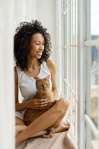 istock Young Woman Relaxing with Her Cat by a Window 2227651483