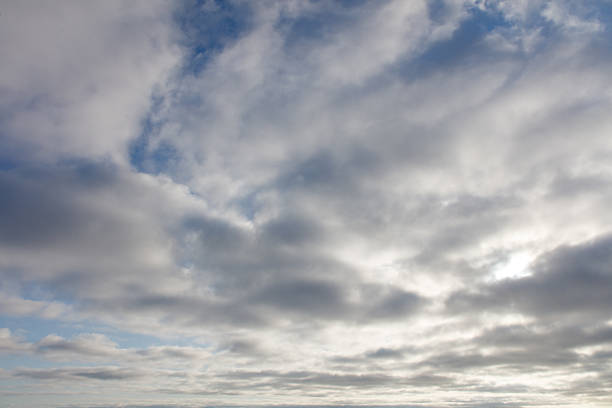 The sky is cloudy and the sun is shining through the clouds. The sky is mostly blue with some white clouds scattered throughout