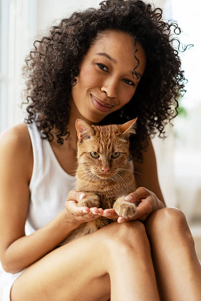 istock Young woman holding a ginger cat on her lap, smiling 2227652545