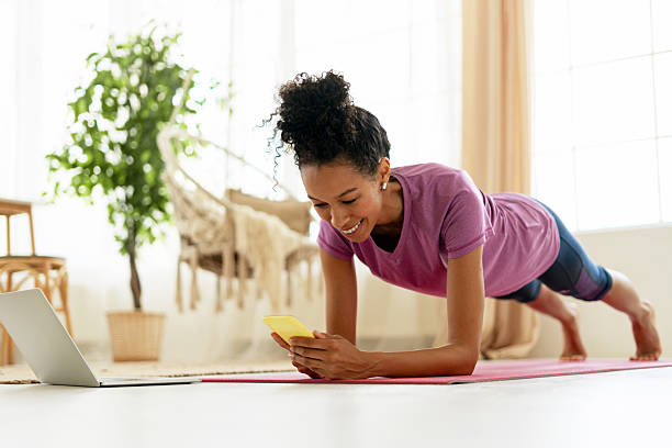 istock Young woman doing plank and using smartphone at home 2227652837