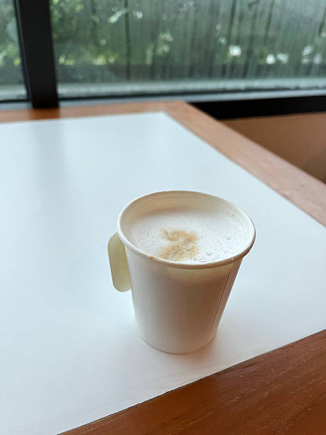 Coffee cup on table in coffee shop with window background.
