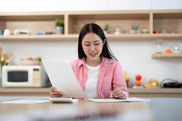 istock Work from Home: Smiling woman reviewing documents with focus 2227656984