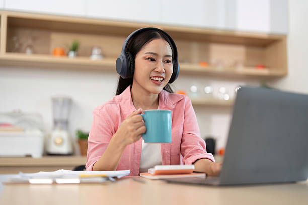 istock Work from Home: Happy woman enjoying coffee while working on laptop 2227657095