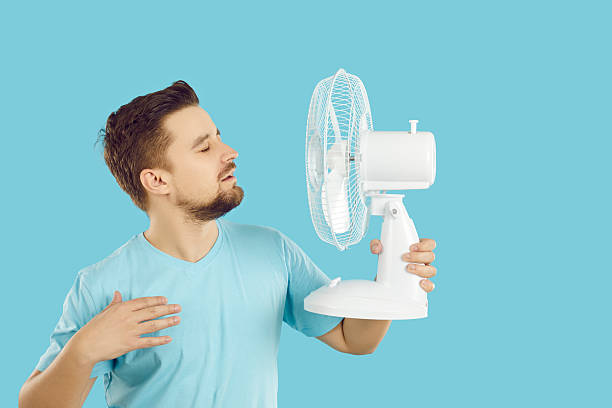 istock Overheated man breathe fresh air from fan 2227657418