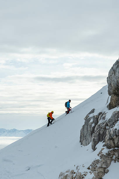 istock Determined Climbers Scaling Snowy Mountain Slope Under Overcast Winter Sky 2227663800