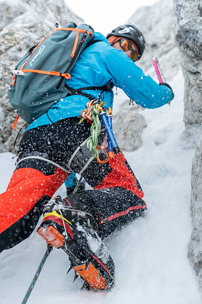 istock Technical Ice Climber Ascending Frozen Waterfall During Winter Storm in Bright Performance Gear 2227663890