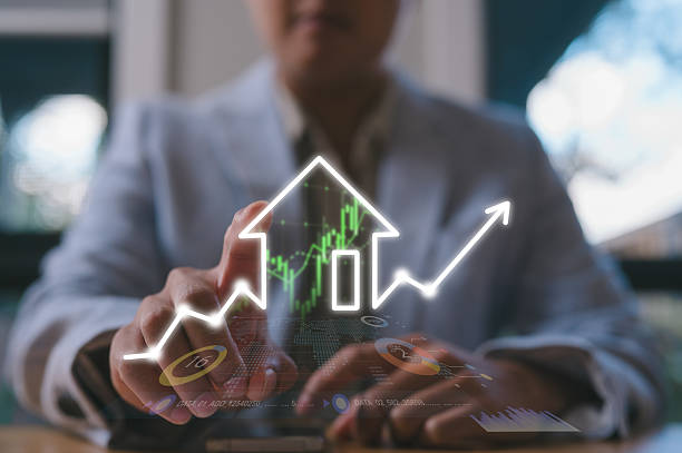 istock Businessman analyzing rising real estate market investment using digital interface with house icon and stock growth chart 2227664155