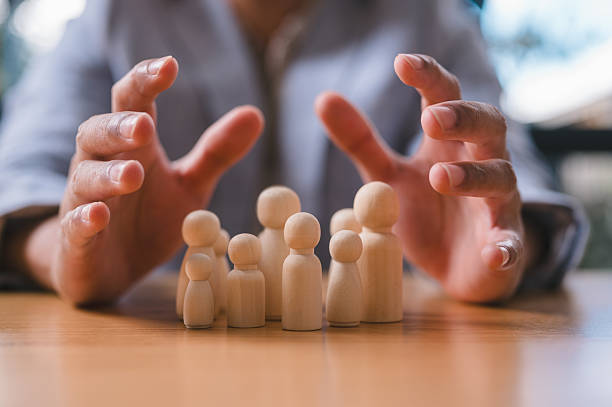 istock Businessman Protecting Team Concept with Hands Over Wooden Figures 2227664214