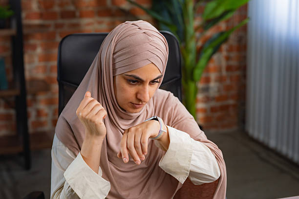 istock Focused Woman in Hijab Using Smartwatch in Modern Office Setting 2227664735