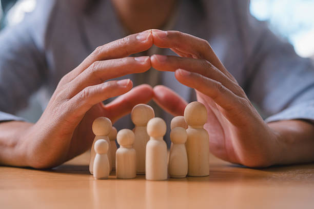 istock Businessman Protecting Team Concept with Hands Over Wooden Figures 2227666165