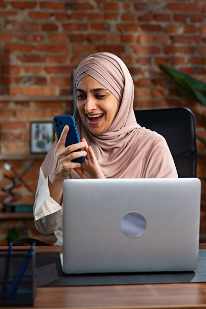 istock Smiling Woman in Hijab Using Smartphone at Modern Workspace 2227667736