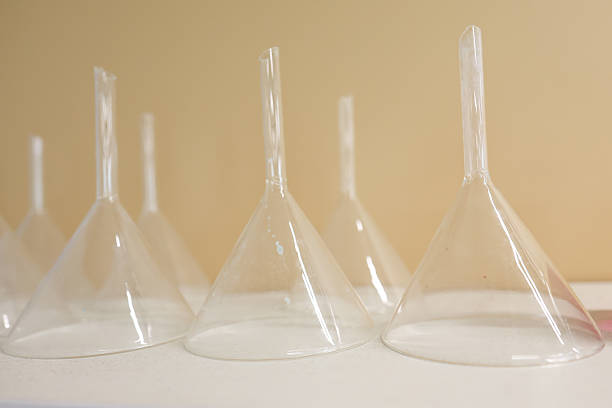 Group of children in lab coats and gloves performing chemistry experiments using glassware, hot plates, scales, and liquid reagents in a modern laboratory setting.
