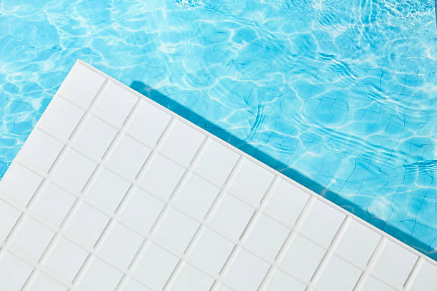 Bright sunlight reflects off clear pool water and smooth white mosaic tiles, forming a clean architectural edge. A blank zone perfect for placing summer-themed mockups or skincare visuals.
