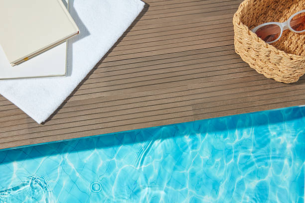 istock Poolside flat lay with notebook, sunglasses, and woven basket on wooden deck by blue water, ideal for summer product mockups and vacation scenes. 2227669587