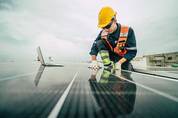 istock Solar technician installs solar panels on rooftop while analyzing data with laptop in urban environment 2227677594