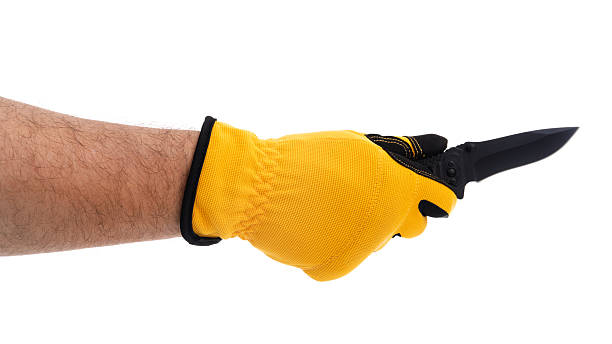 istock Hand in yellow glove holding a black knife 2227678004
