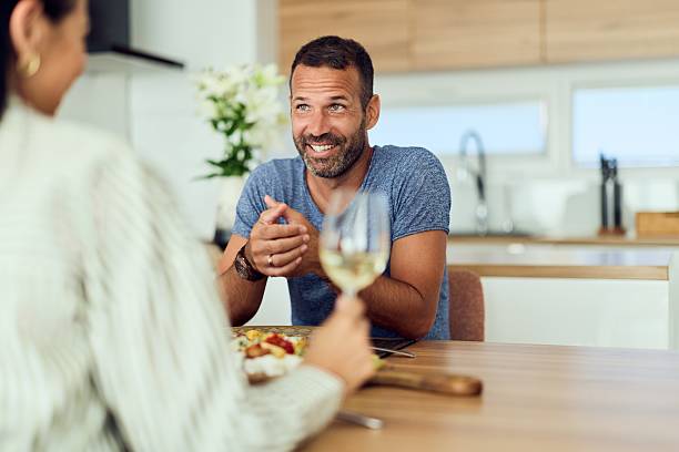 istock Man Smiling and Conversing Over a Meal at a Kitchen Table 2227679820