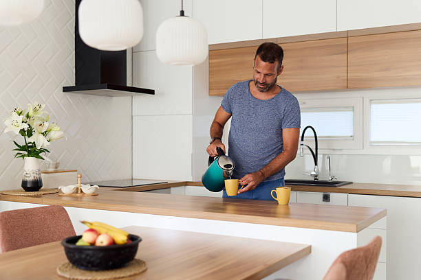 istock Man Pouring Coffee in Modern Kitchen with Minimalistic Interior Design 2227679831