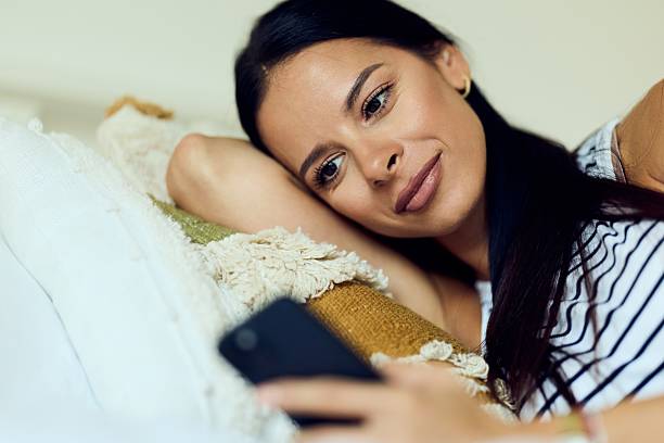 istock Woman Relaxing on Sofa While Using Smartphone at Home 2227679858