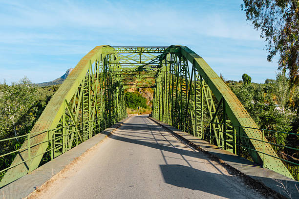 the historic Luis de Arminan bridge spans the Genil river in a peaceful rural setting, uniting two towns, Cuevas de San Marcos and Encinas Reales, across the provinces of Malaga and Cordoba, in Spain