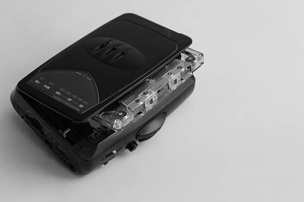 Old audio player with magnetic audio cassette on white background, audio cassette inserted in old black audio player, vintage audio player for cassettes.