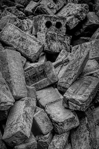 Monochrome still life captures a tumbled pile of weathered, gray bricks with rough textures and varying shapes in artistic composition.