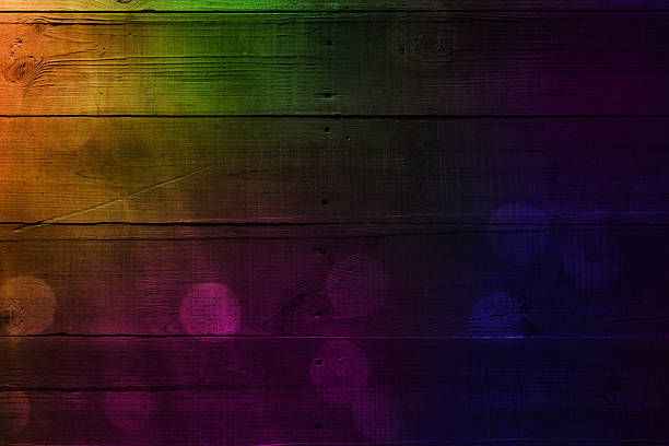 Old weathered rough planks background, dark barn wood with rays of light, colored spots and bokeh. Space for copy.