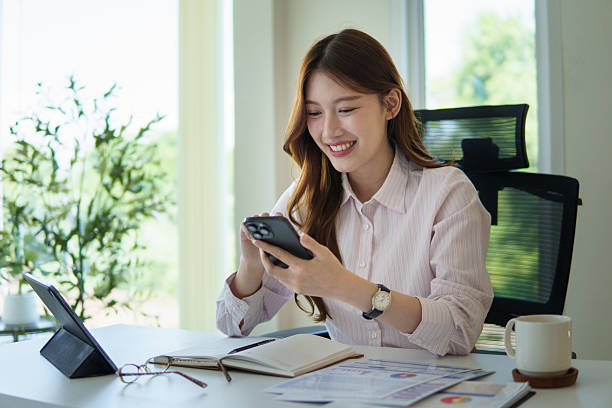 istock Happy female entrepreneur using smartphone while working at modern office desk. 2227696761