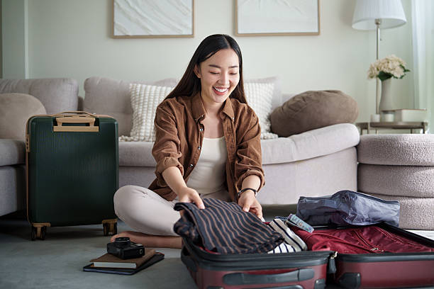 istock Smiling young woman packing clothes into a suitcase, getting ready for a trip at home. 2227697607