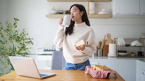 istock Happy woman having a coffee break with breakfast bread and a laptop on kitchen table 2227698017