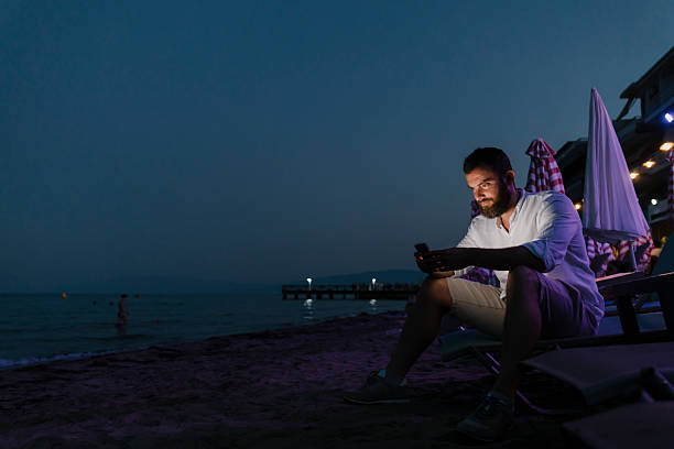 istock Man using smart phone at the beach at dusk 2227698878