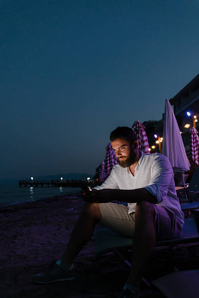 istock Man using smart phone at the beach at dusk 2227698910
