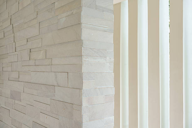 Modern corner of stacked stone wall with modern vertical white panel background