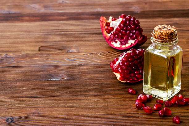 istock Pomegranate seed oil in a glass bottle and fresh fruit on a table, close up 2227700254