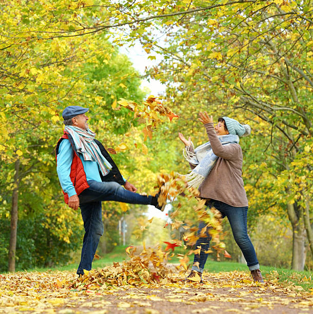 istock Playful Seniors Throwing and Kicking Autumn Leaves 2227700268
