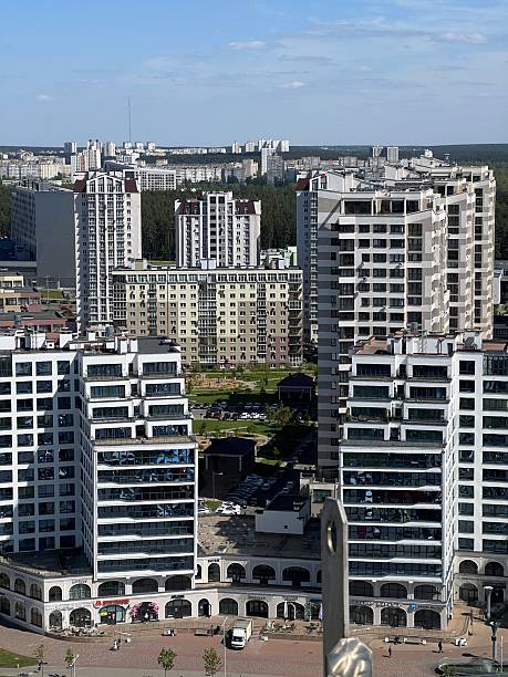 Minsk, Belarus - May 06, 2025: An aerial view of the residential complex in Minsk, Belarus, featuring modern high-rise apartment buildings, a street, and a large parking area. The complex is a prominent architectural project in the city.