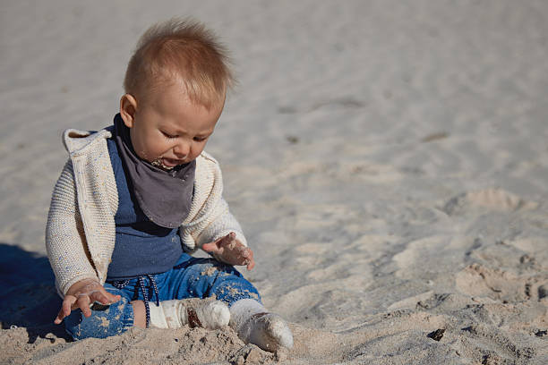 istock Baby Sitting on Sand and Tasting It – Sunny Spring Day 2227703071