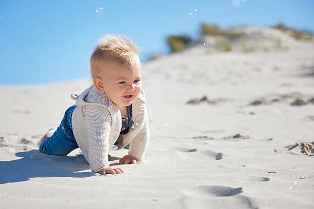 istock Baby Crawling Through Sand with Bubbles Under Blue Sky 2227704292