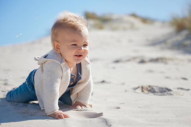 istock Baby Crawling Through Sand with Bubbles Under Blue Sky 2227705024