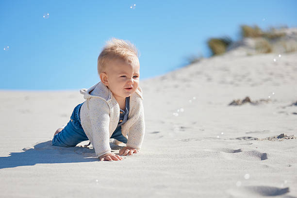istock Baby Crawling Through Sand with Bubbles Under Blue Sky 2227705027