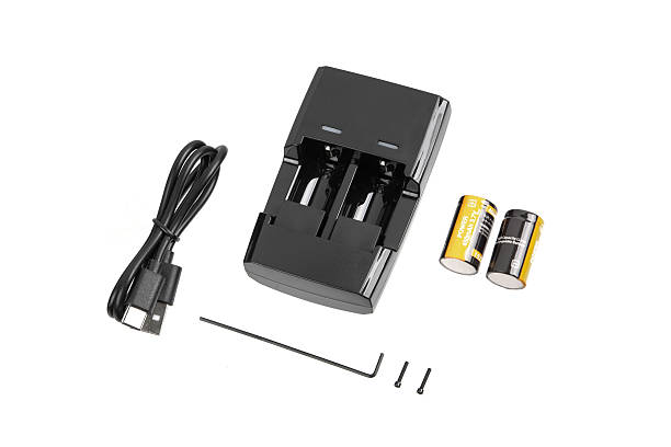 istock A black two-slot battery charger is positioned next to a coiled black USB cable and two orange and black rechargeable batteries, all isolated on a white background. 2227705978