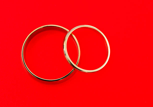 istock Two golden wedding rings on red background 2227706030