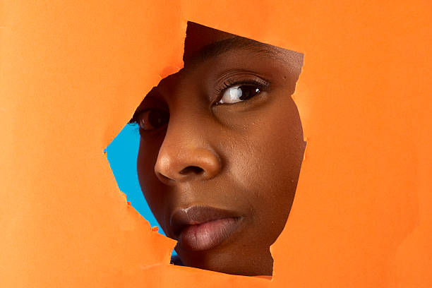 istock Curious model gazing through torn orange paper 2227708759
