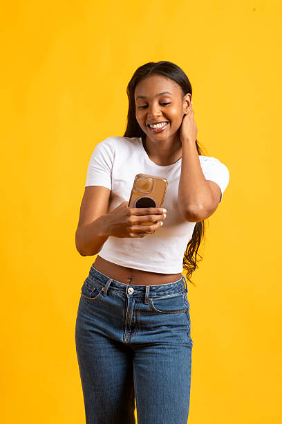 istock Young black woman using smartphone on yellow background 2227708796