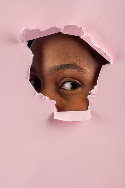 istock Curious young woman peeking through torn pink paper 2227709312